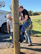 Instructor with student climbing a telephone pole